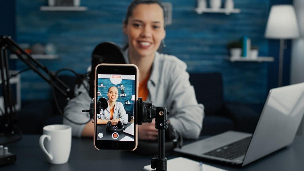 Mulher Influenciadora de mídia social Studio sentada enquanto começa a transmitir da sala de estar com o smartphone