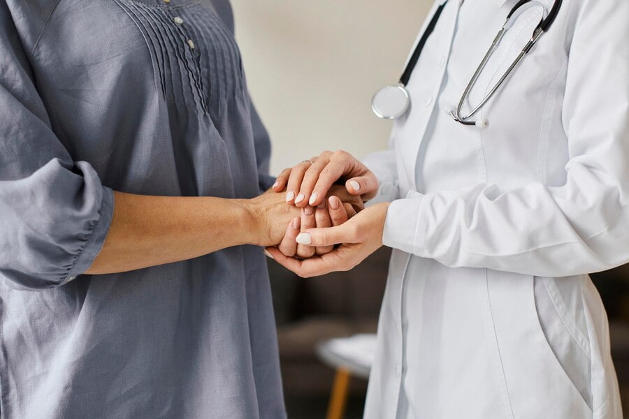 Médica do centro de recuperação segurando as mãos de um paciente mais velho