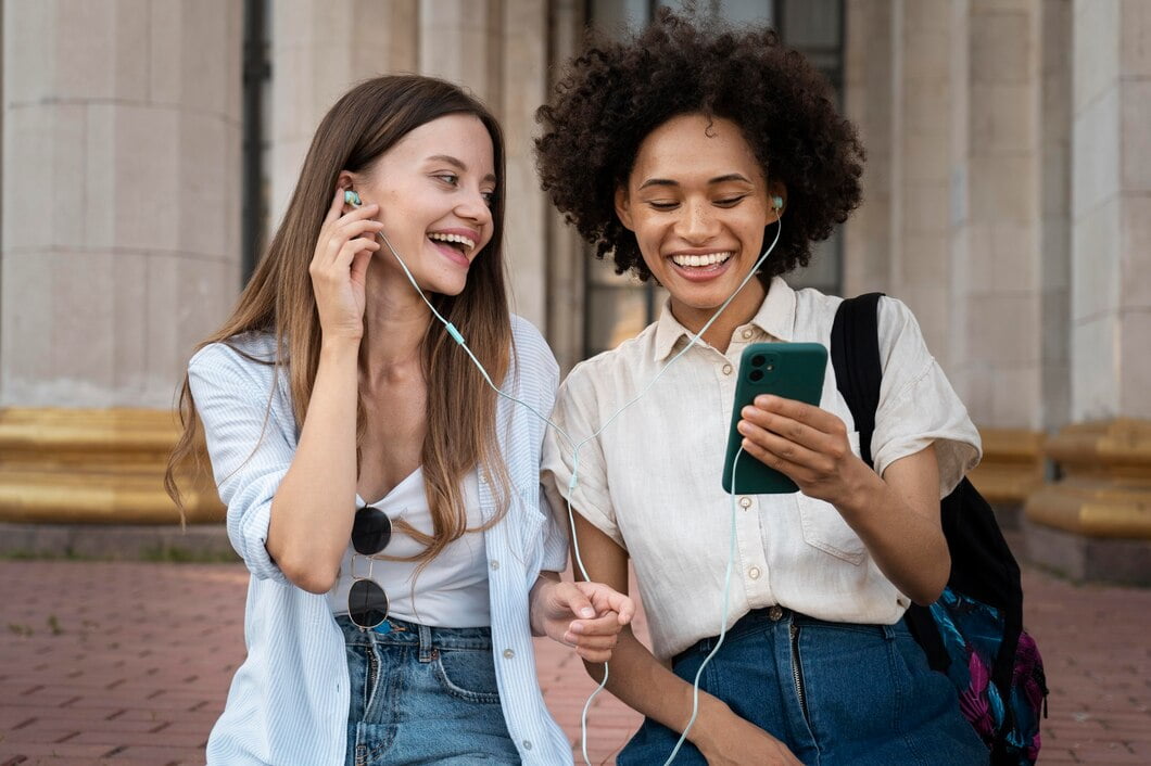 Amigas ouvindo música em fones de ouvido de smartphone ao ar livre