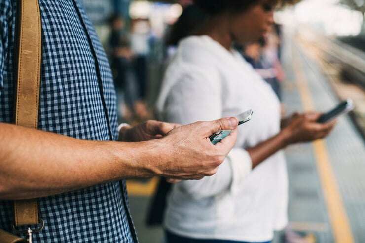 Pessoas usando smartphones em uma plataforma de trem