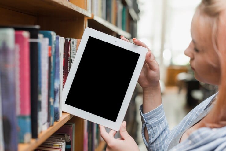 Adolescente pegando tablet da estante
