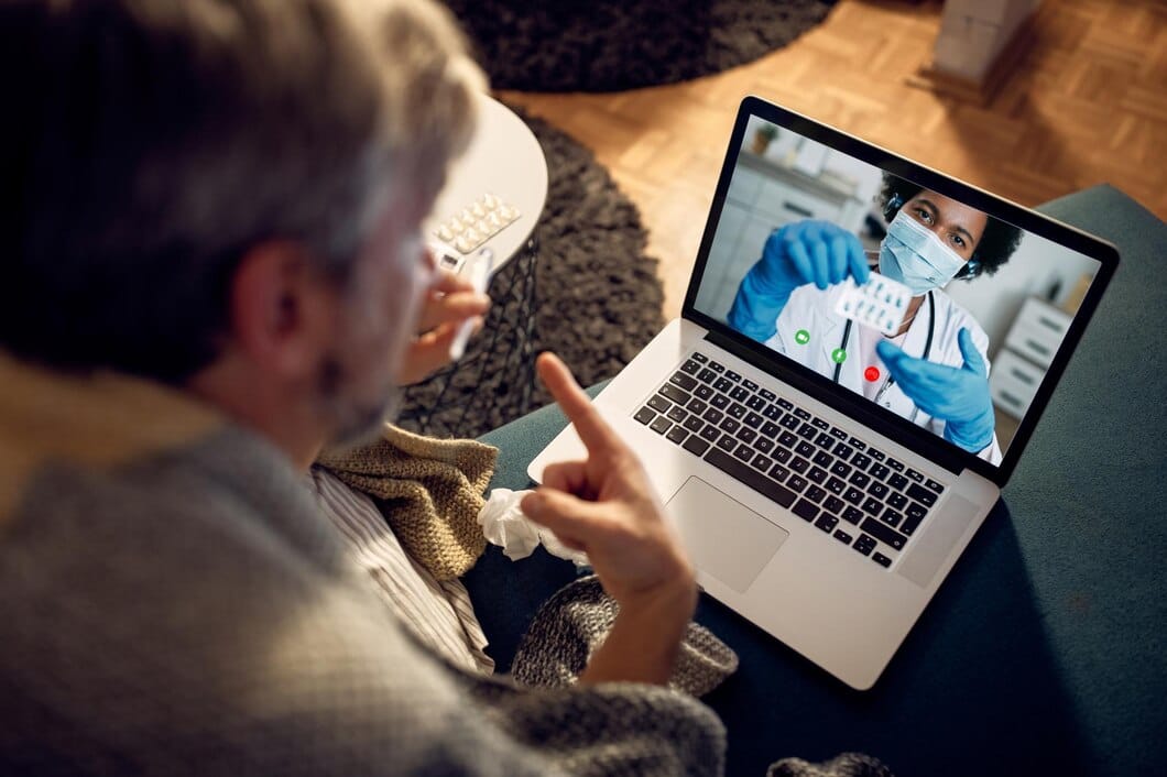 7 estratégias omnichannel para a indústria farmacêutica Closeup de homem tendo chamada de vídeo com seu médico à noite em casa