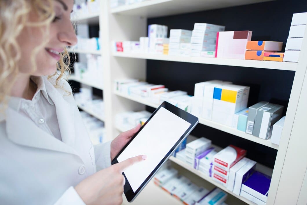 7 Estratégias Omnichannel para a Indústria Farmacêutica Farmacêutico segurando o comprimido pela prateleira cheia de medicamentos