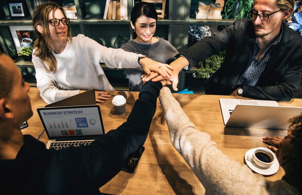 Marketing Colaborativo e o Poder das Parcerias Estratégicas 1 Diversas pessoas empilhando as mãos juntas