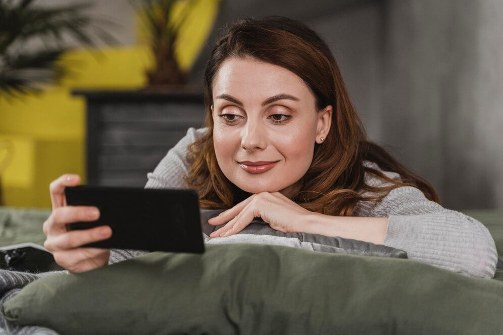 Mulher em tiro médio na cama com telefone
