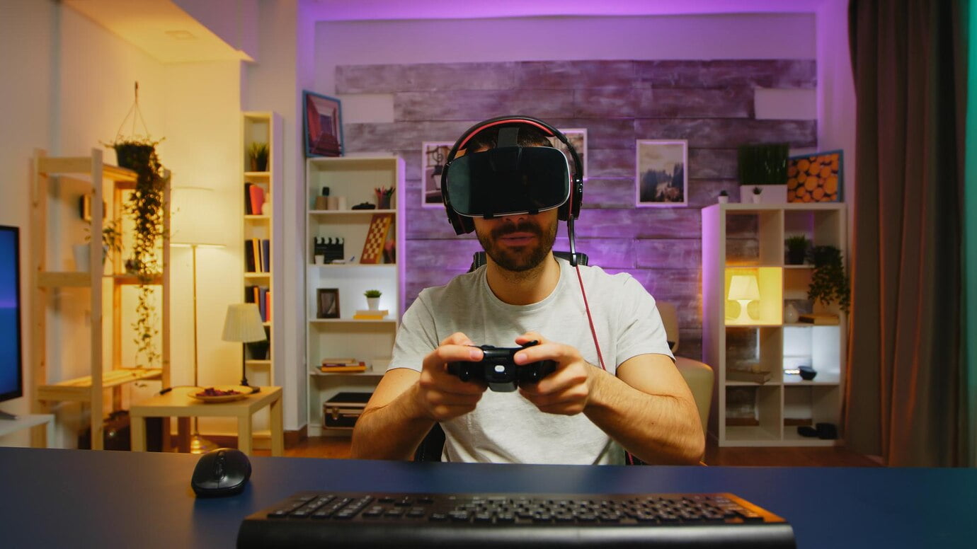 Jovem feliz após sua vitória enquanto jogava videogame usando fone de ouvido de realidade virtual.