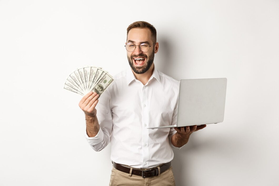 Negócios e e-commerce. Empresário confiante mostrando como trabalhar online, piscando, segurando dinheiro e laptop, em pé