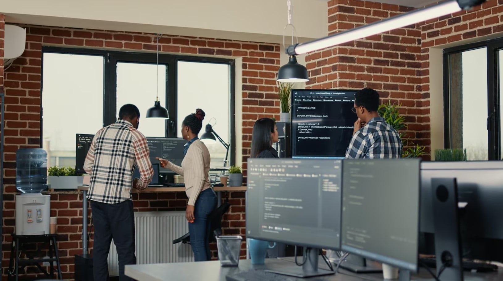 O Que é uma Agência Software House e Como Ela Pode Ajudar? Desenvolvedores de sistemas analisando código na tv de tela de parede