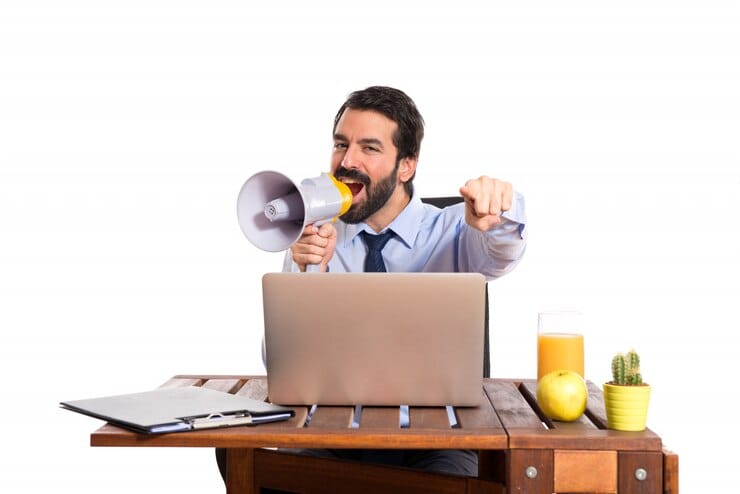 Empresário em seu escritório gritando por megafone