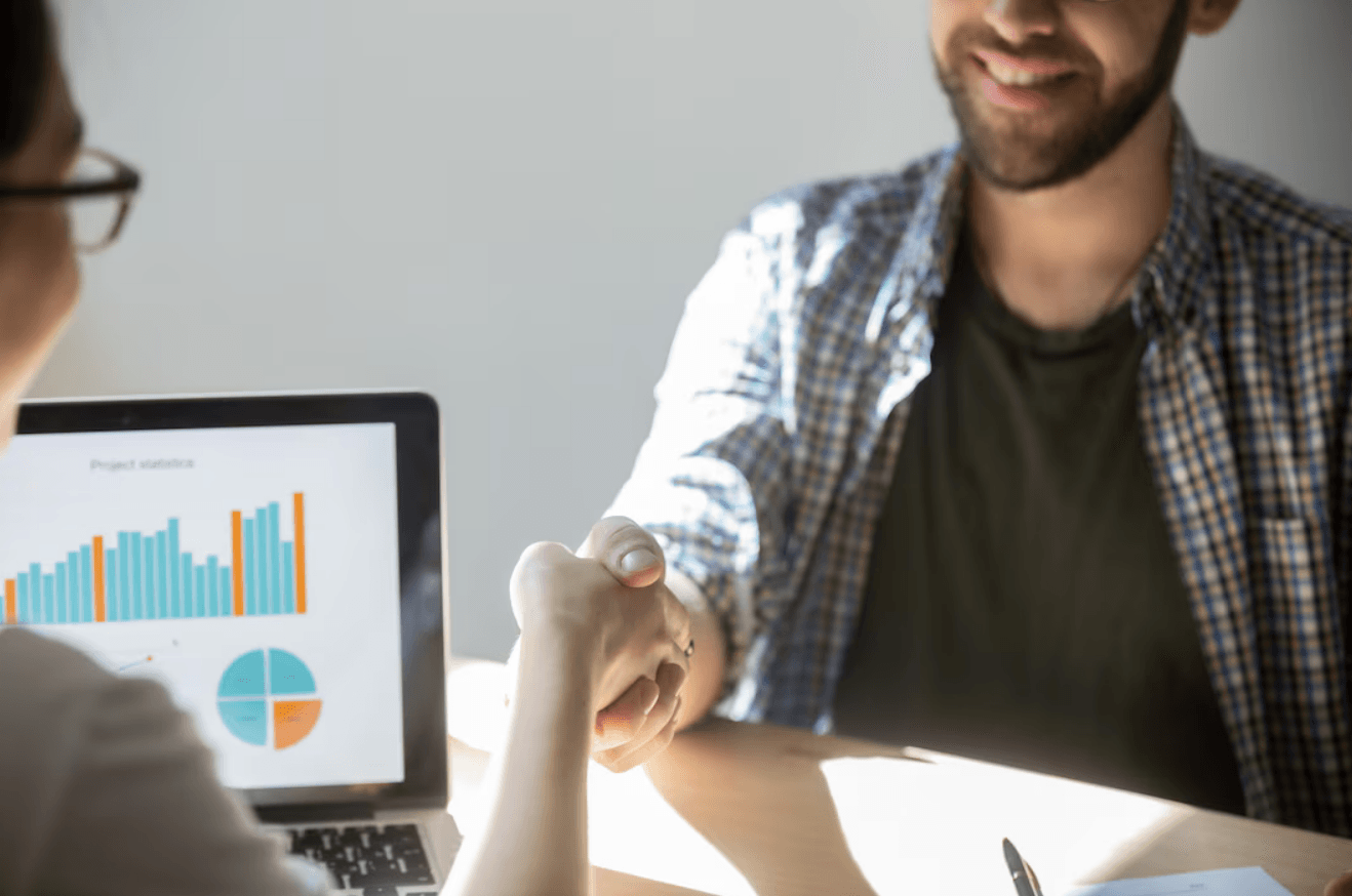 Dois empresários apertam as mãos para selar um acordo com um sorriso.