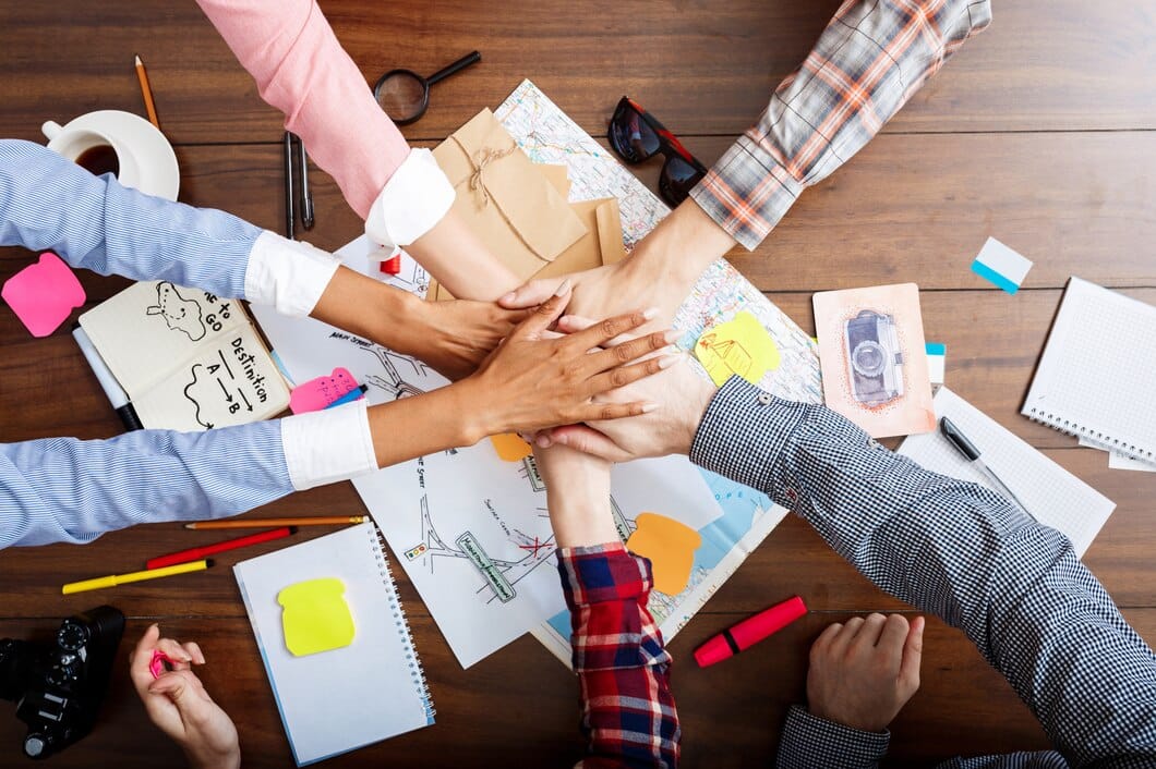 Como comunicar o propósito da marca com eficiência: 7 dicas práticas Empresários as mãos na mesa de madeira com documentos e rascunhos