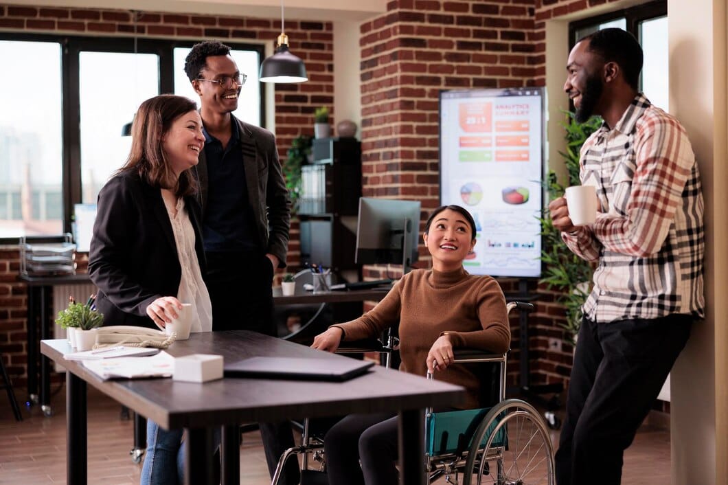 Employer Branding: A Importância da Inclusão e Diversidade 1 Mulher asiática em cadeira de rodas e grupo de pessoas rindo