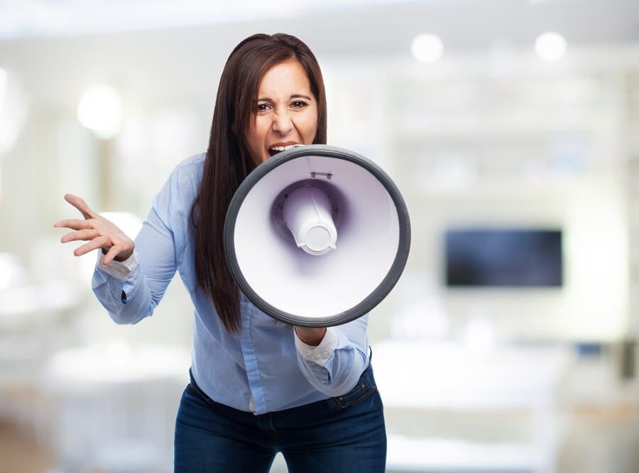 Mulher de negócios forçada usando um alto-falante com fundo borrado