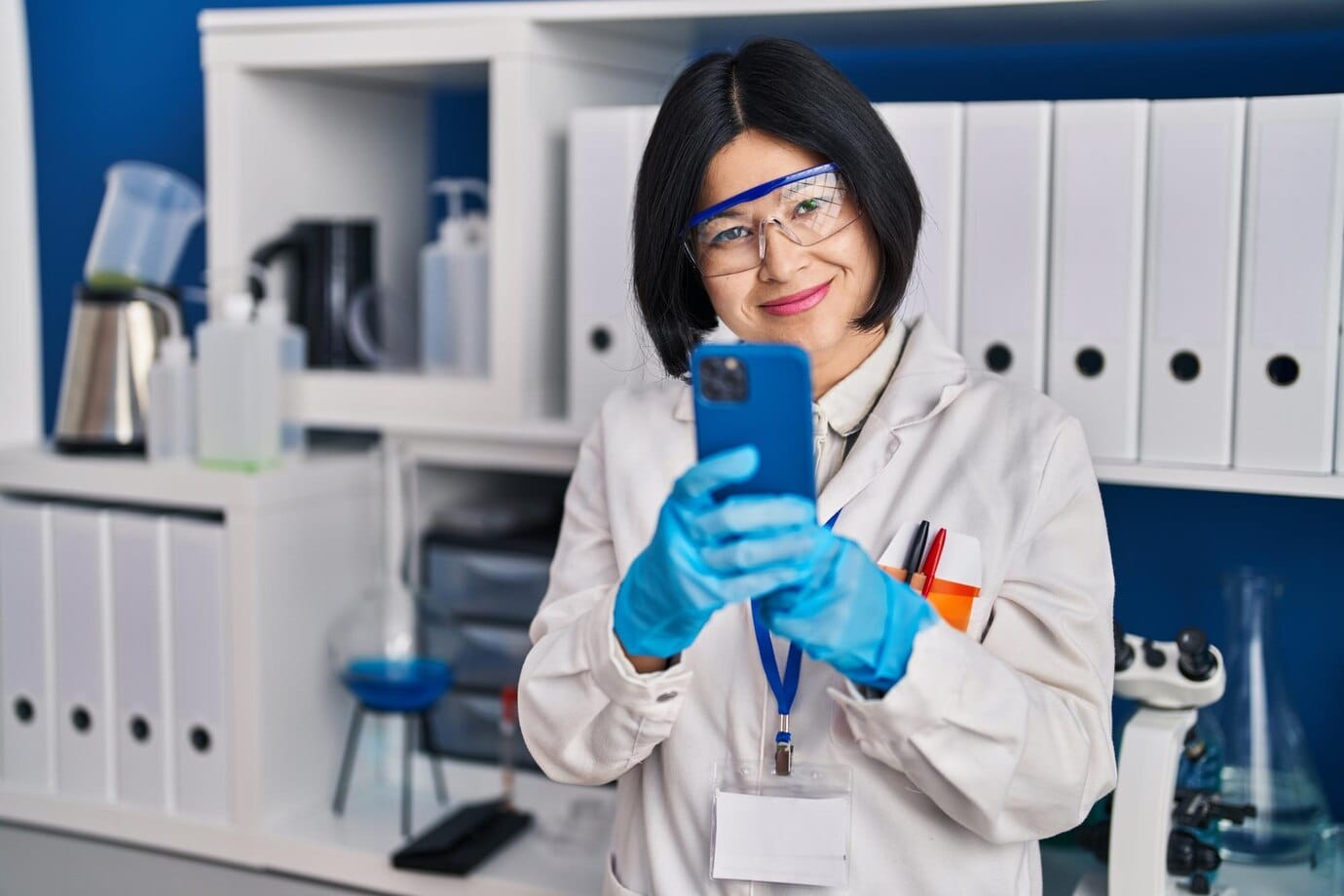 Cientista chinesa jovem usando smartphone trabalhando no laboratório
