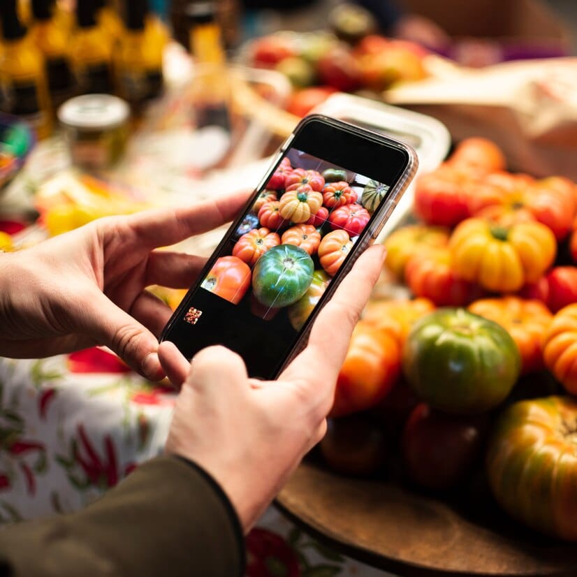 Crie conteúdo atrativo: a isca que pega o cliente Pessoa de close-up, tirando uma foto de legumes