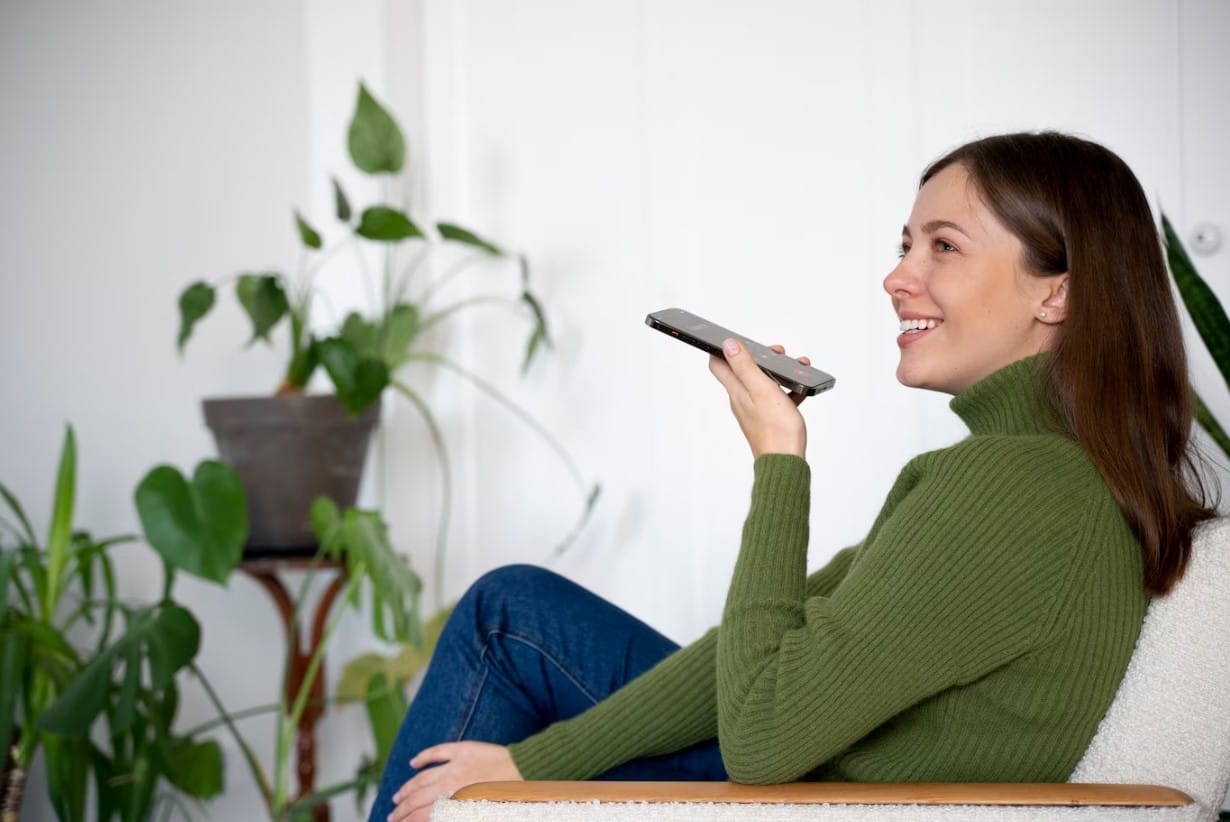 Mulher falando em seu smartphone enquanto está em casa usando o recurso viva-voz