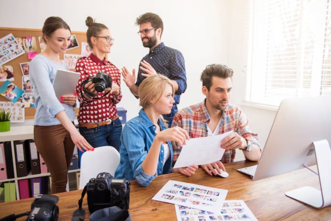 Colegas de trabalho no escritório com câmeras fotográficas e um computador