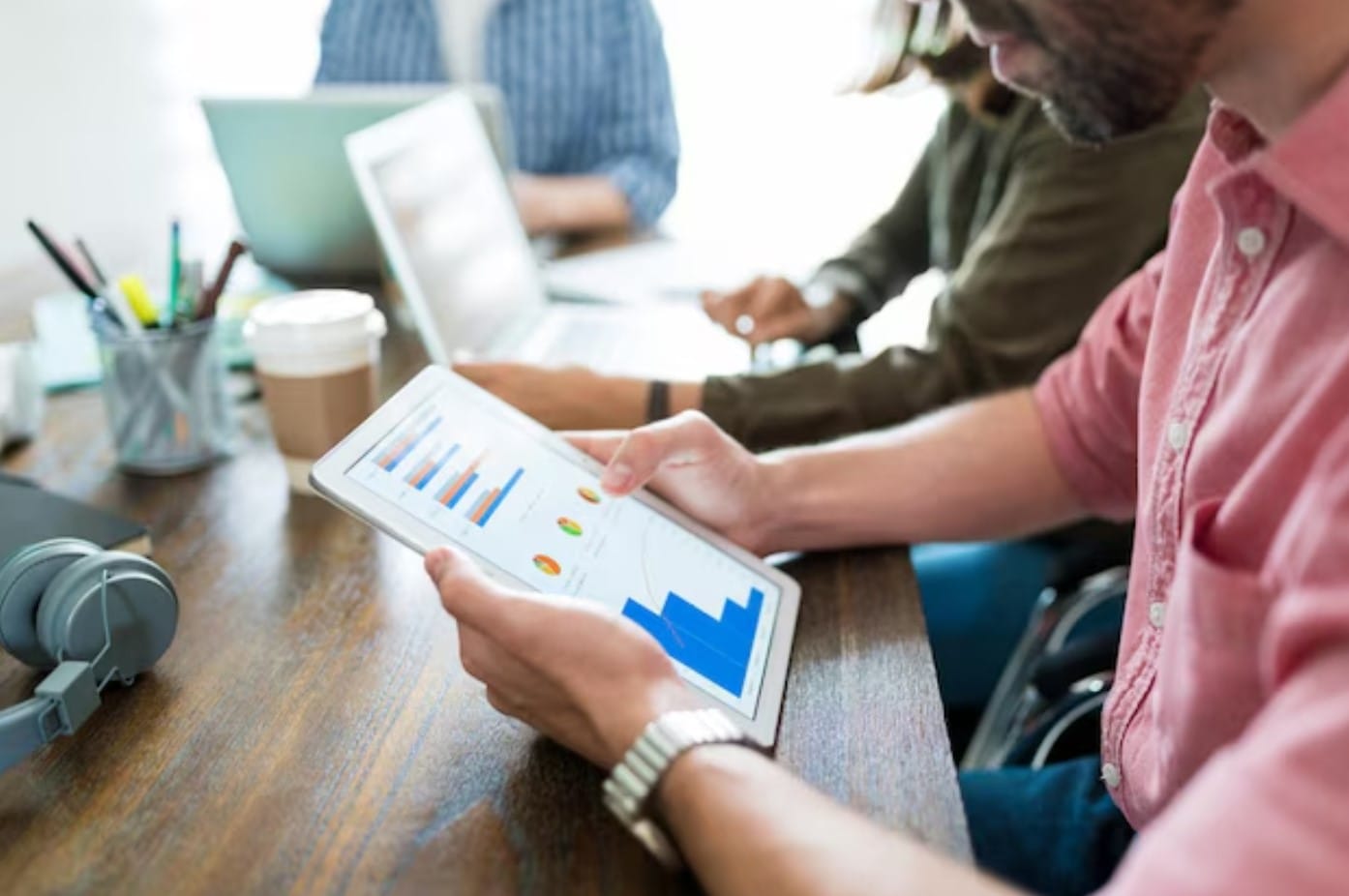O futuro do marketing está nos dados. Você está pronto? Homem de negócios examinando gráficos em tablet digital enquanto planeja com colegas de trabalho na mesa no escritório