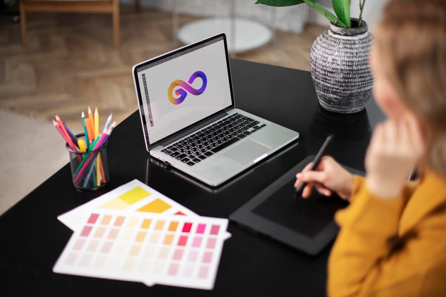 Designer de logotipo feminino trabalhando em seu tablet conectado a um laptop
