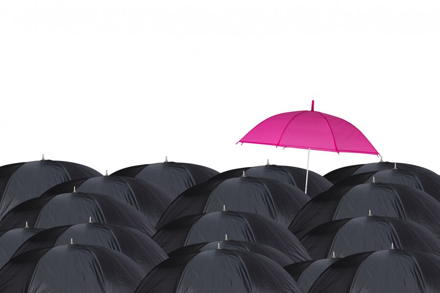 Guarda-chuva rosa entre os guarda-chuvas pretos
