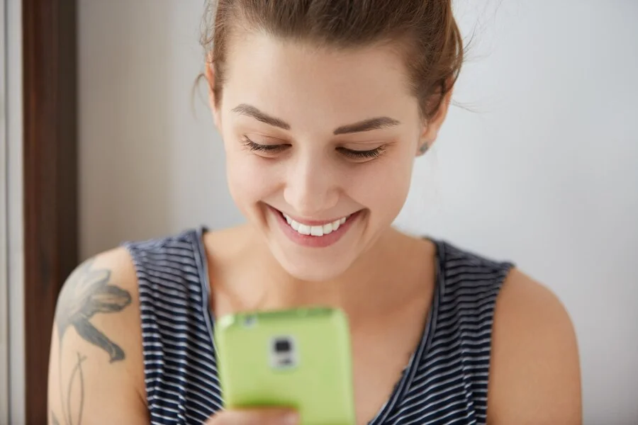 Como Usar o WhatsApp Em Suas Estratégias de Marketing Digital Retrato do close-up de uma mulher de cabelos escuros com pele branca, enviando mensagens para seus amigos
