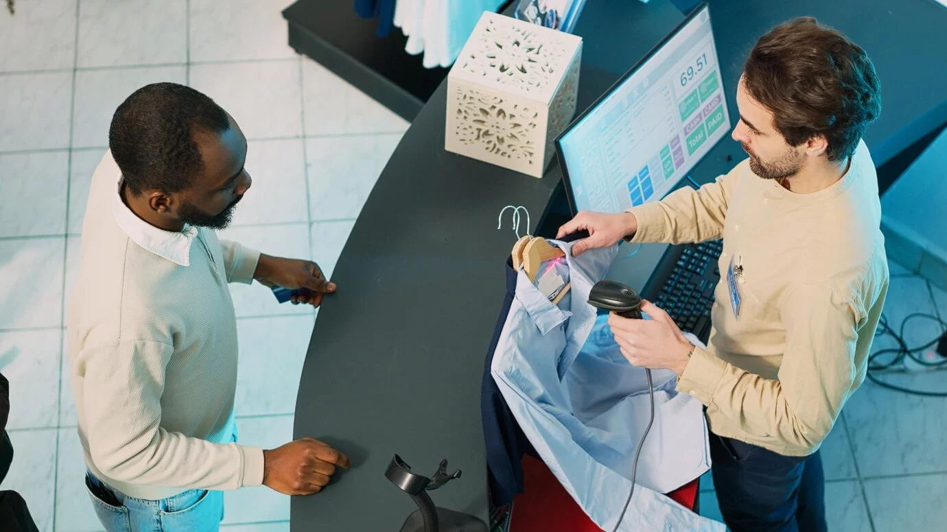 Principais aplicações de IA no varejo Homem afro-americano comprando roupas na caixa registradora da loja, usando cartão para fazer transações