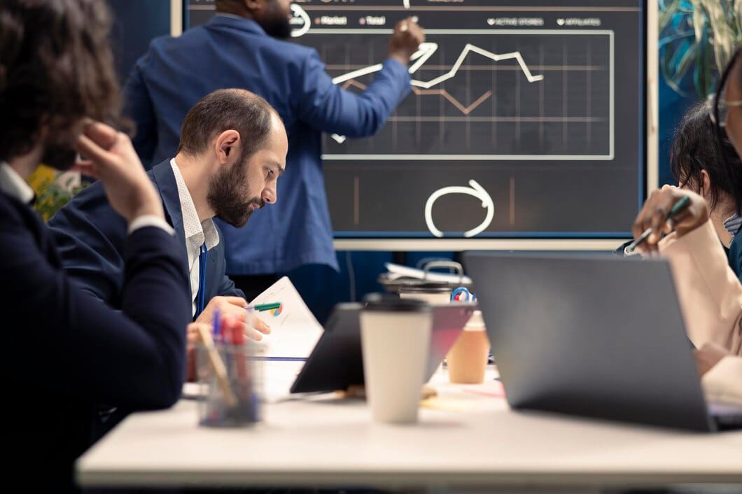 Benchmarking: Como Melhorar suas Estratégias de Marketing Funcionários corporativos examinando o progresso organizacional durante uma reunião
