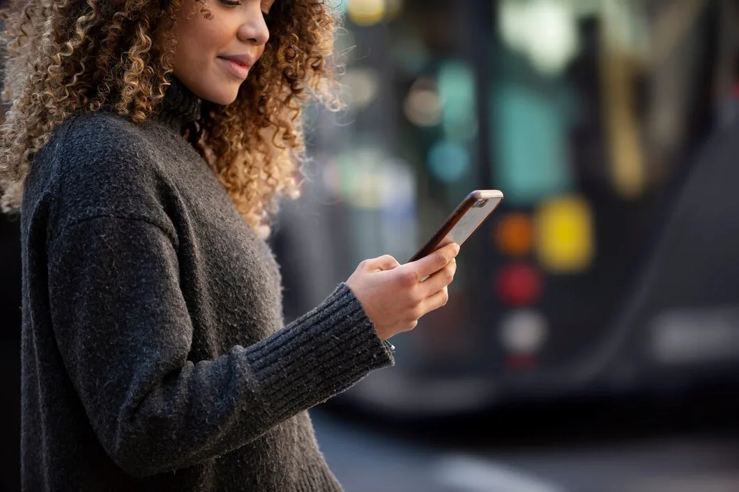 Como Usar Micro-Momentos na Jornada do Consumidor? Jovem mulher usando seu smartphone na cidade
