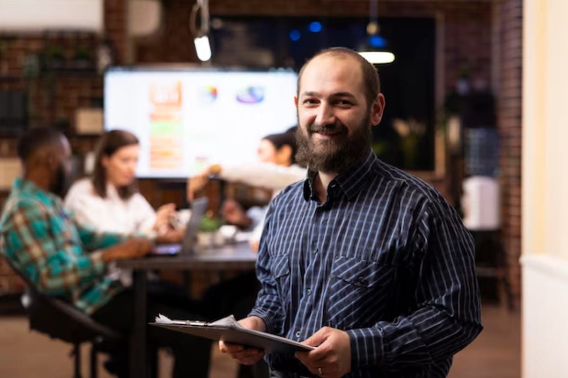 CMO: o que é e o que faz esse profissional? Homem de negócios com caderno sorrindo para a câmera