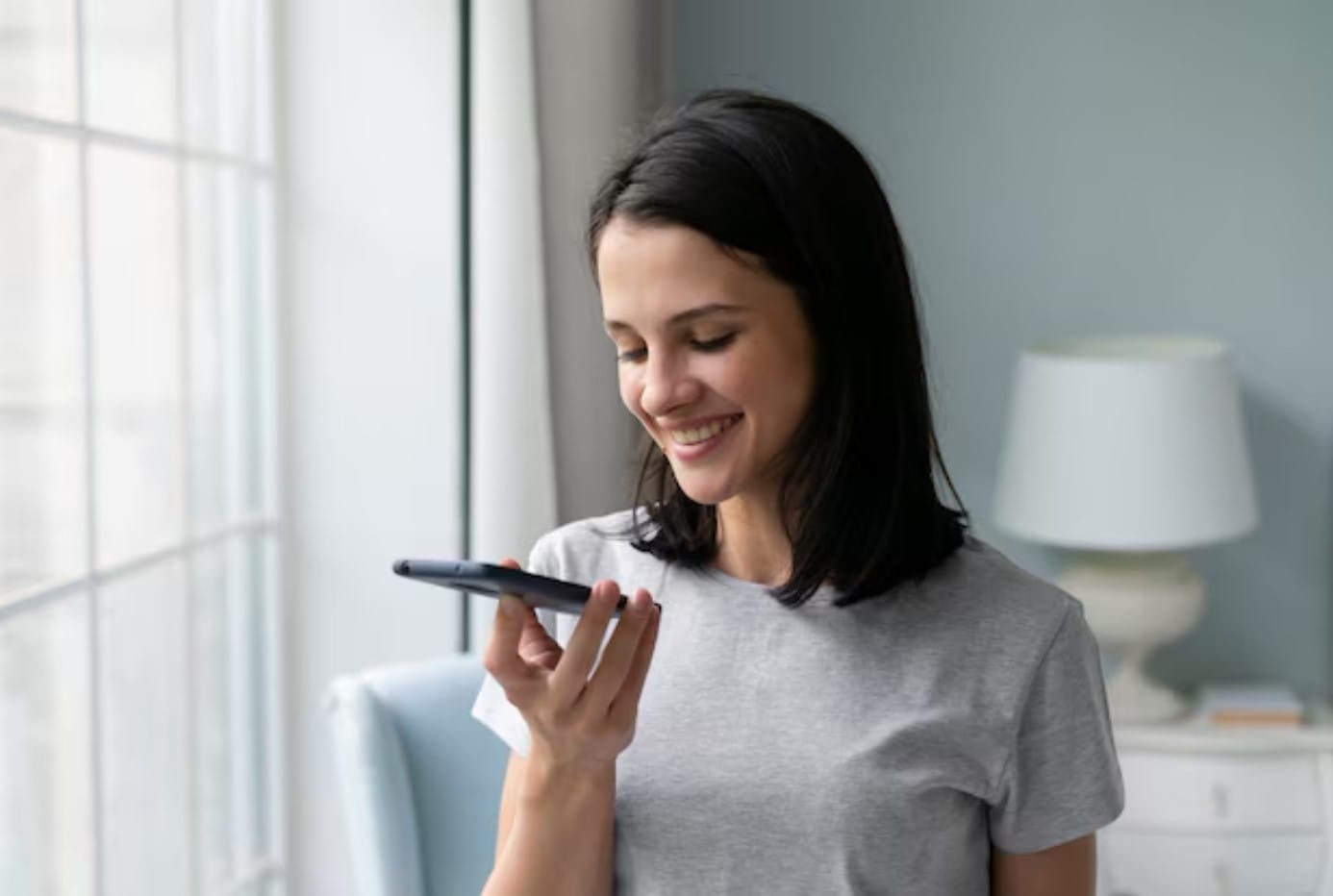 Pesquisa por voz: como adaptar sua estratégia de conteúdo Mulher jovem segurando o telefone