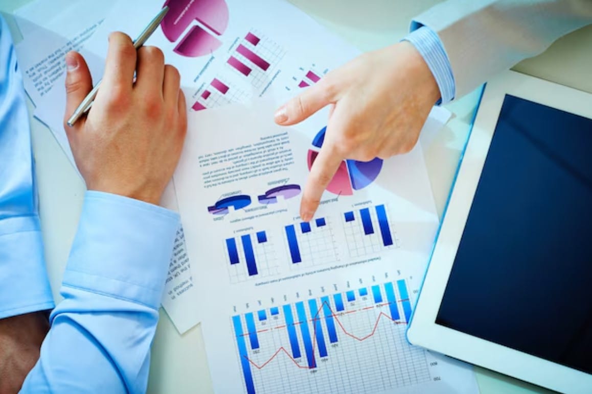 Como implementar o growth marketing na prática Vista de cima de colegas de trabalho falando de um gráfico de barras
