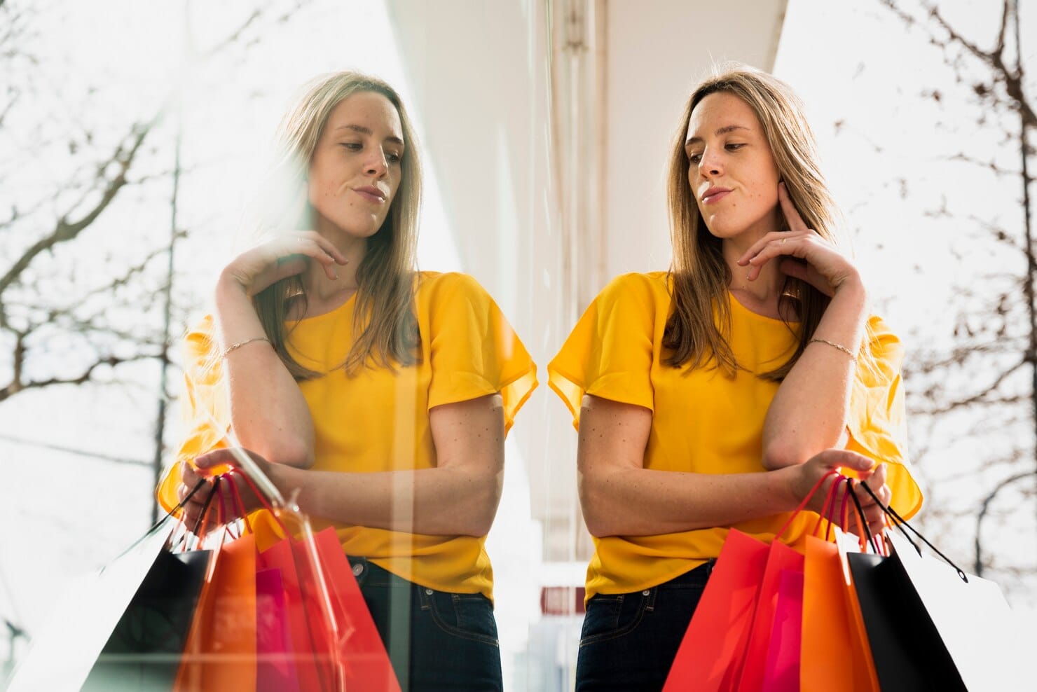 Como criar campanhas de marketing baseadas em comportamento Menina olhando seu reflexo, segurando sacolas de compras