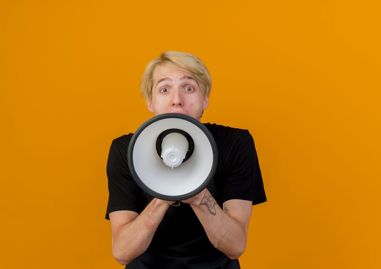Adaptação sem perder a essência da marca Barbeiro profissional de avental gritando para o megafone em pé sobre a parede laranja