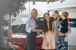 Família com filho escolhendo um carro em uma loja de automóveis