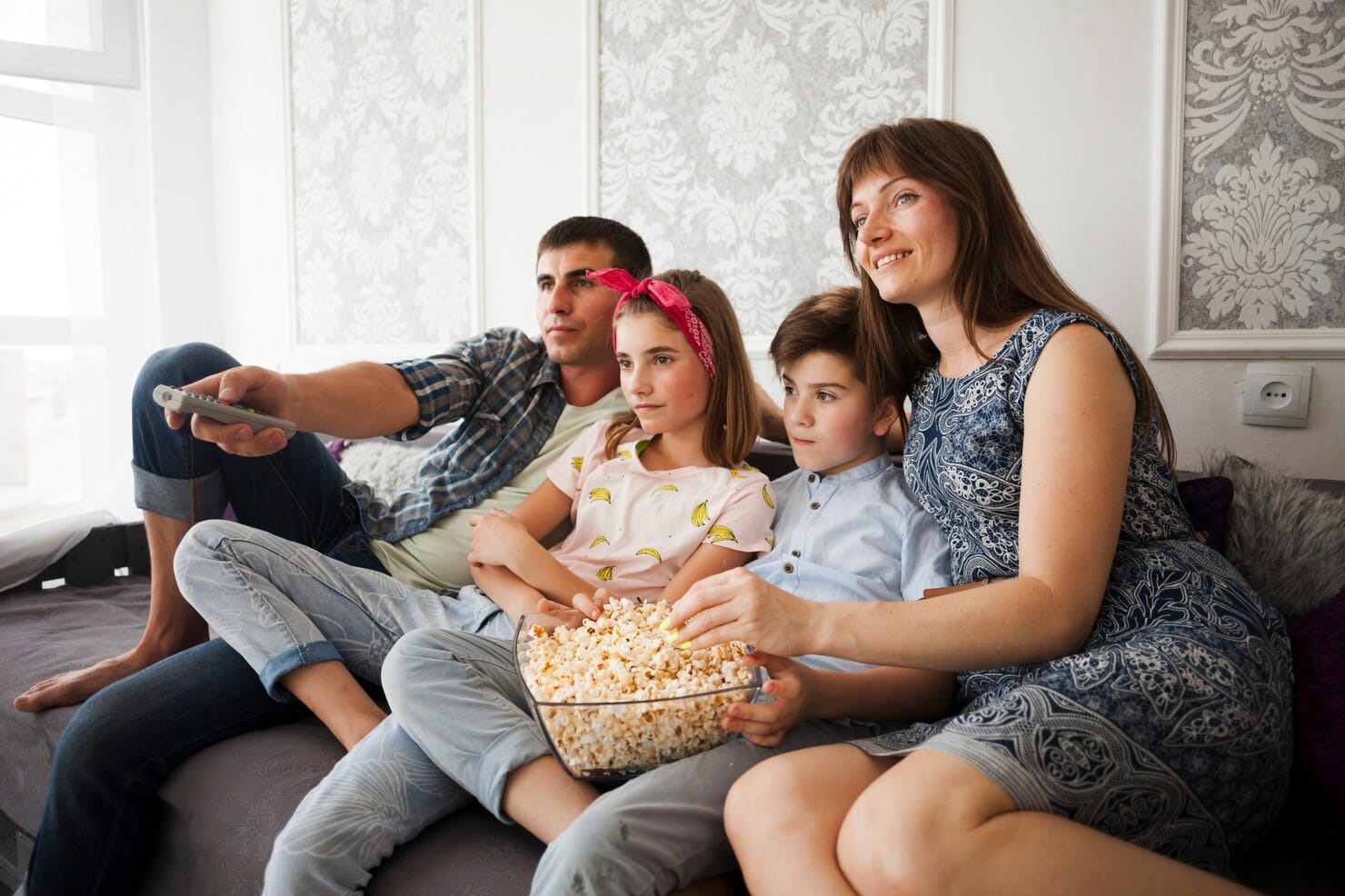 Família comendo pipoca durante assistir televisão em casa